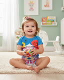 Child sitting on a carpeted floor in a nursery holding a colorful toy.
