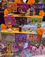 Display of colorful items including a bottle of Coca-Cola, flowers, and decorative objects on a shelf.
