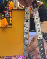 Person measuring a yellow object with a tape measure against a colorful background