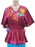Mannequin wearing a pink top with floral embroidery and blue skirt on a white background