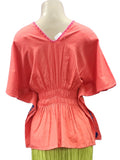 Mannequin wearing a coral top and green skirt on a white background