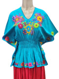 Colorful blouse with floral embroidery on a mannequin against a white background